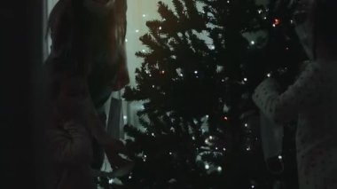 Koruyucu maskeler takan çocuklu aile, 2021 yılının Noel ağacını yüz maskeleriyle süslüyor..