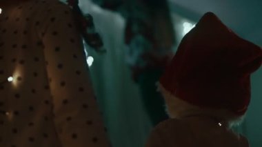 Evlerini dekore eden aile, ışıkları asan anne ve izleyen mutlu çocuklar..