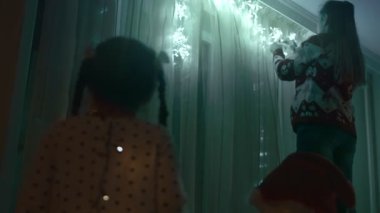 Mutlu çocuklar hamile annelerine bakıp Noel ışıklarını asıp dans ediyorlar..