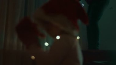 Hamile anne Noel ışıklarını asarken Noel Baba şapkalı mutlu çocuk dans ediyor..