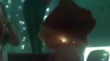 Noel tatili için evlerini dekore eden Noel Baba şapkalı küçük kız ışıklarla oynuyor..