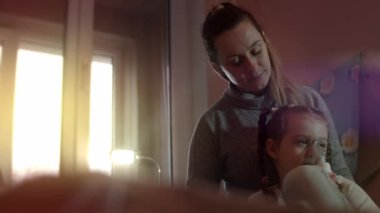 Anne, kızına evde solunum terapisi için yardım ediyor..