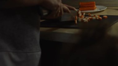 Yürüyen çocuk annesinin yengeç çubuklarını kesişini izliyor..