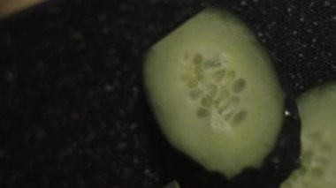 Kesme tahtasında taze salatalık dilimleri.