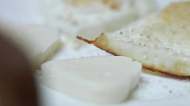 Kahveyi kaşıkla karıştırıp yanında bir tabak kızarmış yumurta ve mozzarella peyniri servis ediyor..