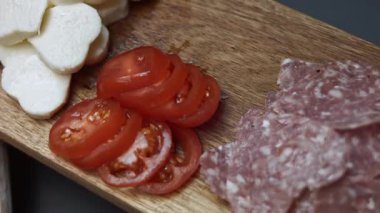 Dilimlenmiş kiraz domatesleri, kalp şeklinde salam sosis ve ahşap tepside mozzarella ısırıkları..