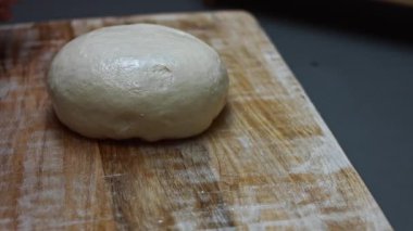 Tahta kesme tahtasından pizza için taze hamuru ikiye bölüyor..