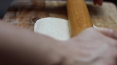 Tahta kesme tahtasının üzerinde pizza için taze hamuru yuvarlıyorum..