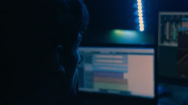 Ses teknisyeni ses düzeltmesini yapıyor. Stüdyoda ışık zayıf..