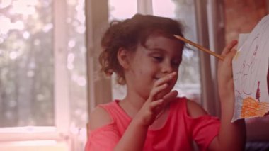 Bir çocuk balkonun camına gökkuşağı çizer. Renkli gökkuşağı resimleri, koronavirüs salgını sırasındaki umudu yayıyor. Covid-19 salgını. Ev kilitlenmesi