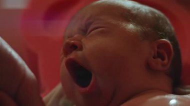 Anne onu yıkarken yeni doğan bebek esniyor..