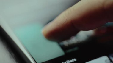 Bir akıllı telefon üzerinde bir akış uygulamasının içeriğini kaydıran parmak.