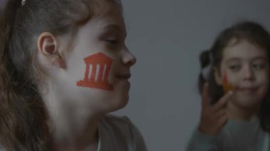 Yüzlerinde mimari temalı resimlerle gülümseyen iki küçük kız. Neşeli bir şekilde dans ediyor. Mimarlık konsepti.