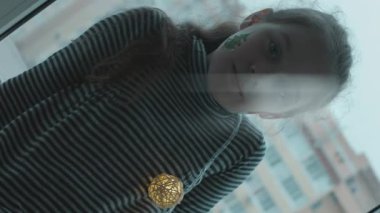 Ciddi küçük bir kızın Noel ağacı resmi var, kameraya bakıyor..