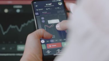 USD JPY döviz çiftini izlemek için mobil borsa uygulaması kullanan kişi, gerçek zamanlı fiyat grafiği.