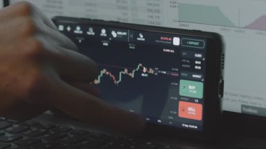 Tüccar, akıllı telefon ekranındaki finansal ticaret uygulaması ile etkileşime geçiyor.