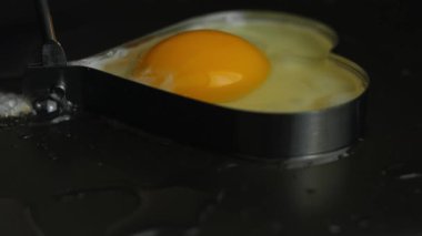 Kırık bir yumurta, kalp şeklinde bir yumurta halkası içinde kızartılıyor..
