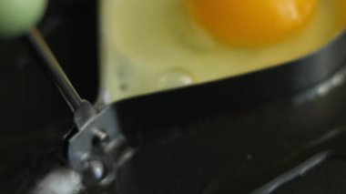 Temalı kahvaltı için yumurta pişirmek için kalp şeklinde bir yumurta halkası kullanmak..