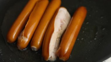 Sosisler kızartılıyor, iki sosis ikiye bölünmüş..