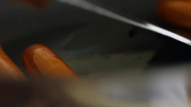 Kızarmış sosisleri tavadan çıkarıp kağıt peçetelerle kaplı bir tabağa koyuyorsun..