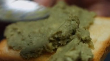 Guacamole 'yi bir dilim kızarmış ekmeğin üzerine serpiştirme görüntüsü.