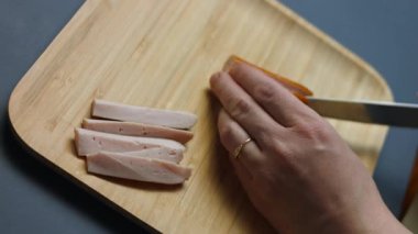 Tahta kesme tahtasının üzerinde sosis dilimleyen biri..