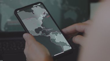 Cep telefonu ekranında dünya haritasıyla küresel siber saldırı. İnternet ağı iletişimi siber saldırı altında. Dünya çapında virüs yayılımı çevrimiçi. Yakın çekim.