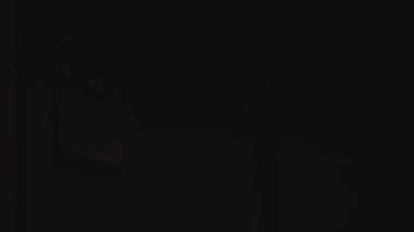 Kadın asansörden çıkar ve karanlık bir salona yalnız gider. Binada ışık zayıf. Odaklanma.