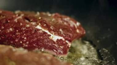 Kaba tuza bulanmış çiğ sığır filetosu kızartma tavasında pişiyor, yakından bak..