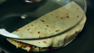 Quesadilla cam kapakla kaplı bir tavada pişiriliyor..