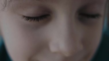 Mavi gözlü, neşeli, sarışın bir kızın makro portresi kameraya bakıyor..