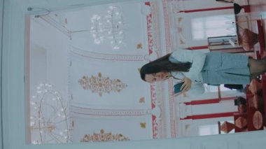 Genç bayan tarih müzesini ziyaret ediyor ve bilgi aramak için akıllı telefonu kullanıyor..