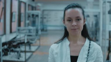 Tarih müzesini ziyaret eden genç bir kadın, kameraya bakıyor, ağır çekimde..