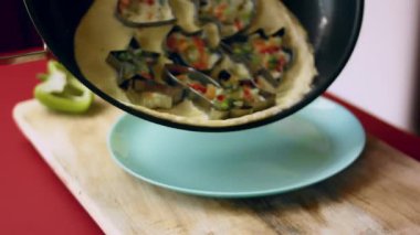 Pişmiş sebzeli omleti kızartma tavasından servis tabağına taşımak..