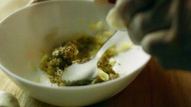 Sarımsak püresini tuz ve bitki baharatlarıyla kaşıkla karıştırıyorum..