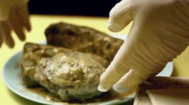 Kişi kavrulmuş sığır filetosunu etli böreğin üzerine koyuyor..