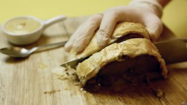 İnsan, Wellington bifteğini ahşap bir kesme tahtasıyla dilimliyor..