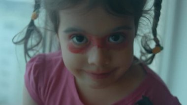 Küçük kız eğlence için dudaklarını ve göz kapaklarını maske olarak boyadı..