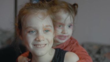 Komik küçük kızlar gülmek için yüzlerini ruj ve göz farı ile boyadılar. Yavaş çekim.