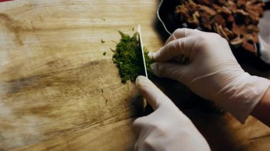 Taze dereotu, ahşap bir yüzeyde ince ince doğranır..