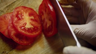 Birinin taze domatesleri ince ince dilimlediği yakın plan..