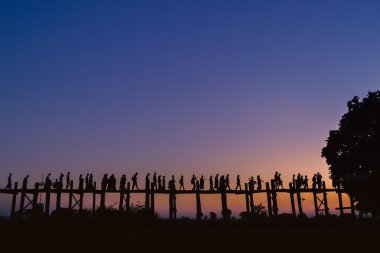 Yerliler akşam Teak köprüde batımında, Mandalay, Myanmar yürüme..