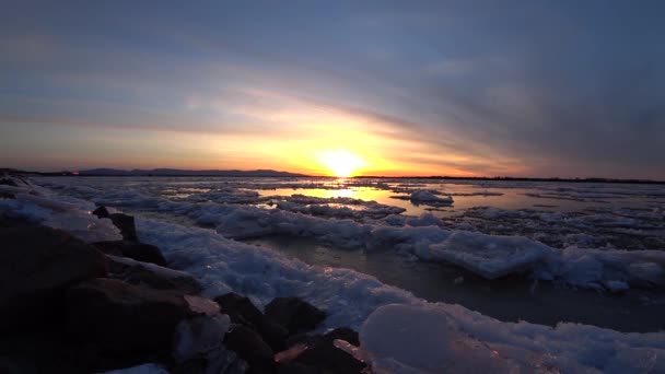 Puesta de sol roja sobre el hielo que corre de un gran río. — Vídeos de Stock