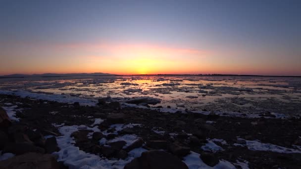 Beautiful red sunset over the icy river, ice drift on the river — Stock Video