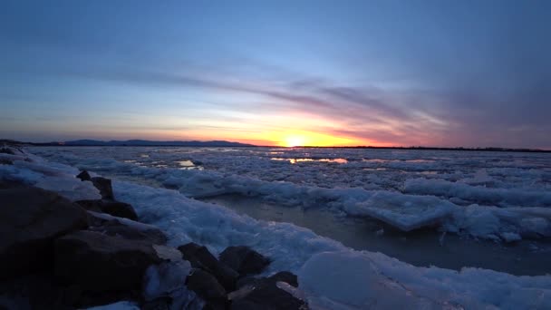 Red sunset over the running ice of a large river. — Stock Video