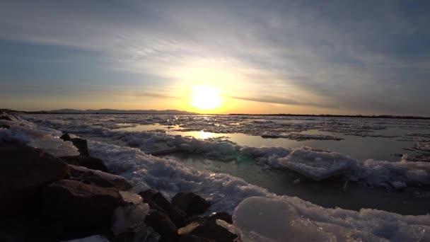 Gyönyörű vörös-sárga naplemente a jeges folyó felett, jégsodródás — Stock videók