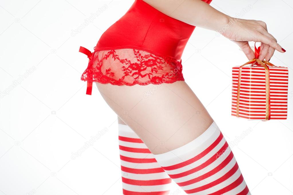 Sexy butt of woman wearing Christmas holiday lingerie and sexy Santa stockings with gift