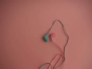Pembe ve mavi elektrikli kulaklıklar pembe arka planda yatar.