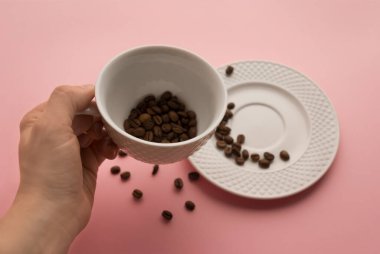  Beyaz bir fincanın içinde koyu kahve çekirdekleri, parlak pembe bir zemin üzerinde b