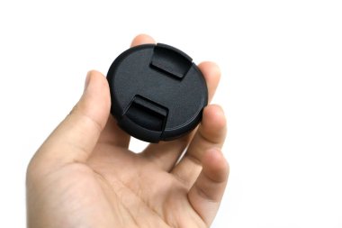 Adamın eli beyaz arka planda izole edilmiş bir lens kapağı tutuyor.